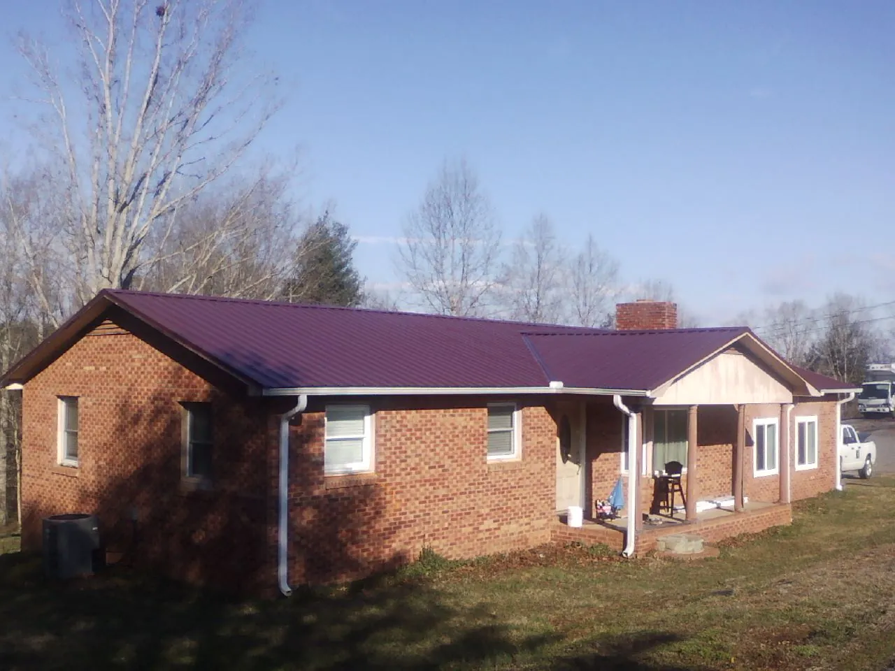 Burgundy metal roof on a brick ranch home with a new addition in Southern Pines