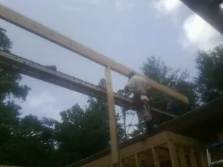 Carpenter setting a ridge beam over a new addition frame — Ice Dam Removal by Roofing Brothers in Southern Pines