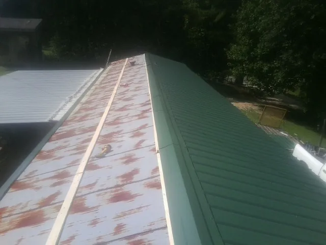 Old rusted panels beside newly installed green metal roofing — Wind Damage Roof Repair by Roofing Brothers in Southern Pines