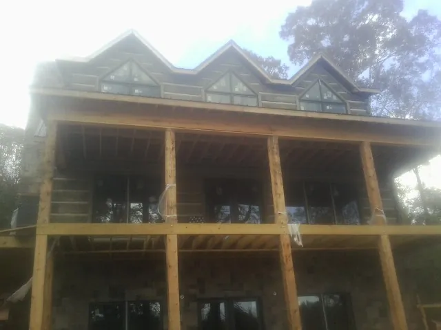 Dormers and porch framing on a large log home under construction — Roof Coating work by our crew in Southern Pines