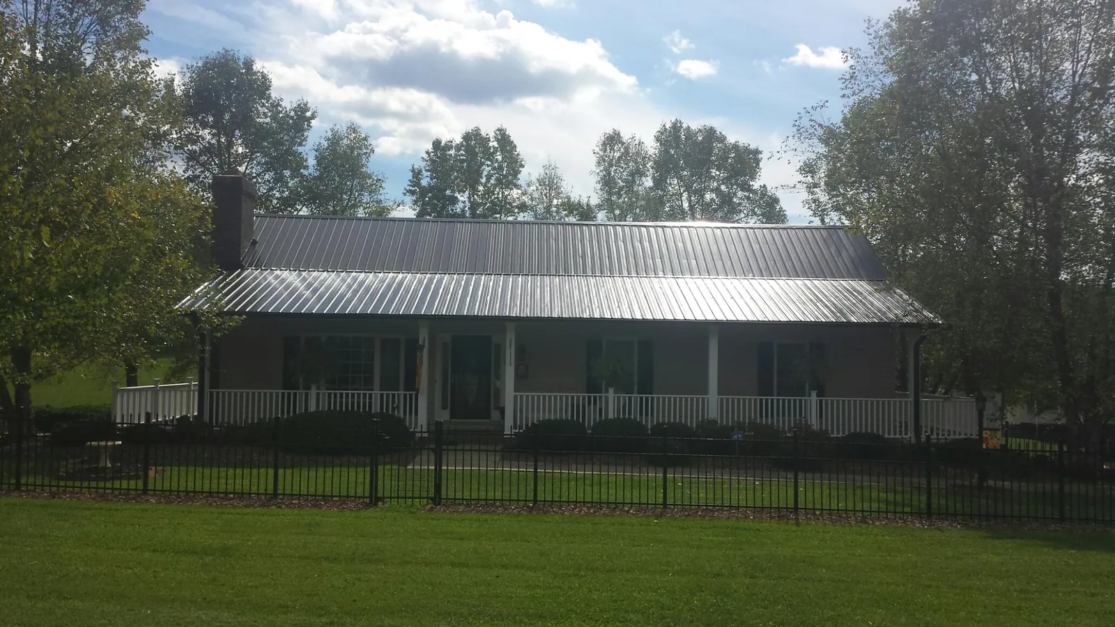Gray metal roof on a brick ranch with a full width front porch — Gutter Guard Installation work by our crew in Southern Pines