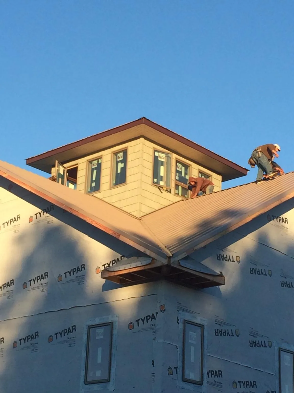 Roofers working around a rooftop cupola on a new metal roof at sunset — Roof Waterproofing in Southern Pines by Roofing Brothers